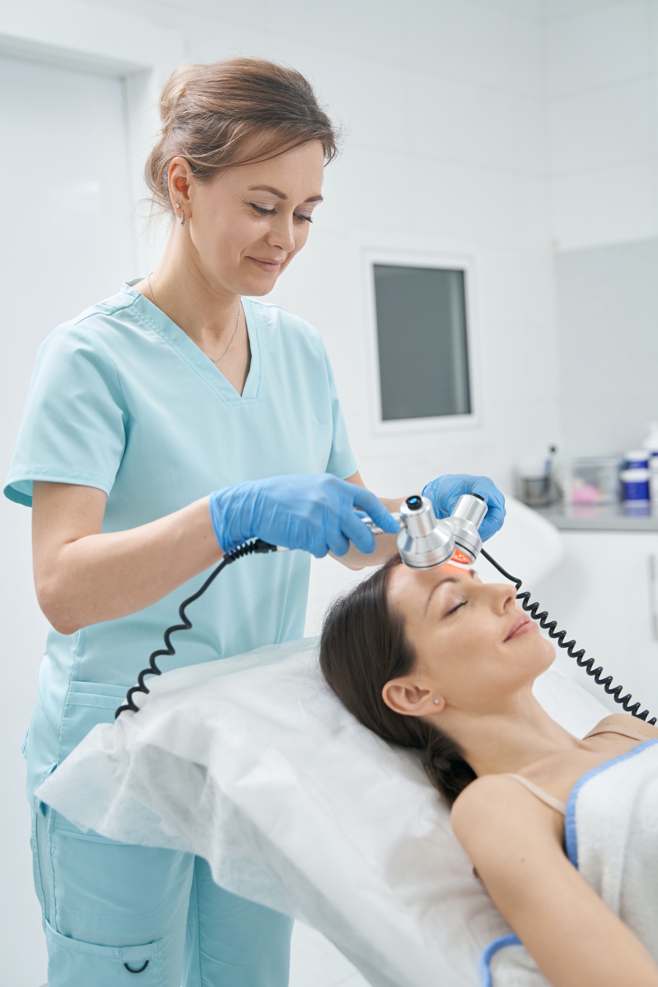 Cosmetologist performing radiofrequency facial treatment